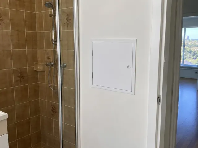 Neat access panel on a white bathroom wall beside a tiled shower in Wolli Creek